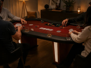 MRC Poker home game setup with players, cards, chips, and drinks around a red felt poker table in a warm indoor lounge.